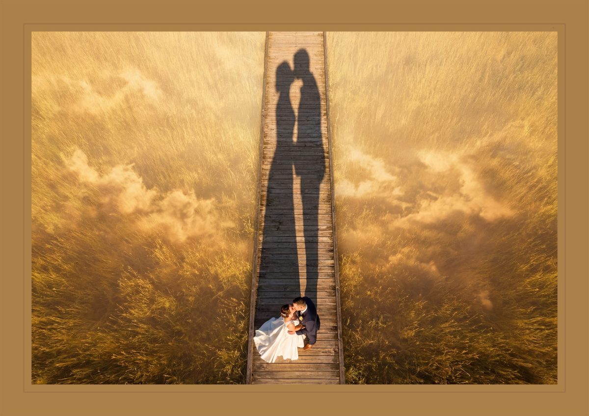 An overhead drone view of a bride and groom kissing on a wooden walkway during a Vermont wedding photography session.